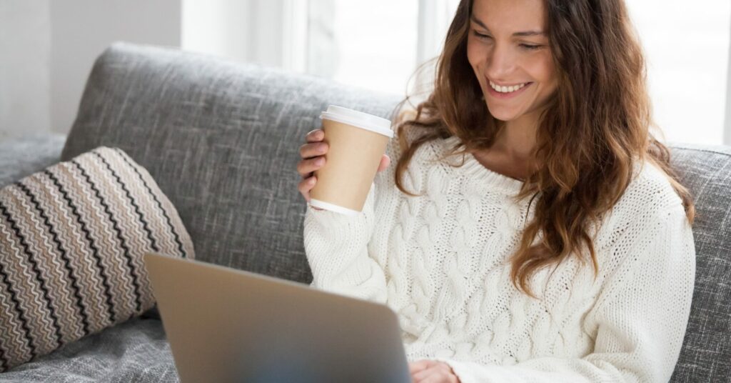 Smiling young woman using laptop at home.