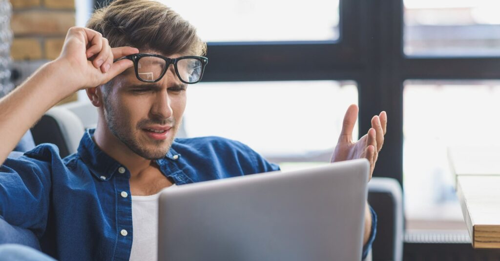 Confused man staring at laptop.