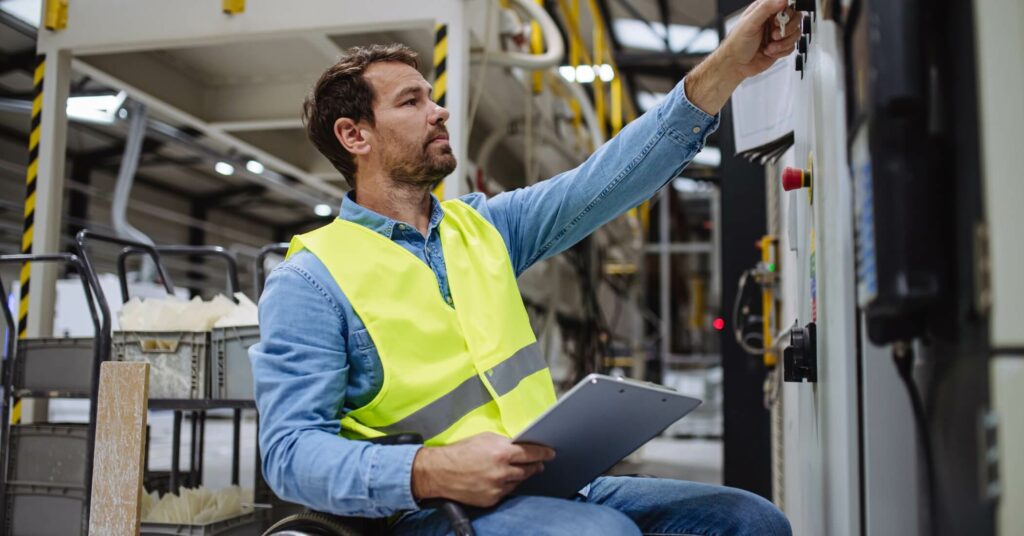 Portrait of man in wheelchair working in modern industrial factory.